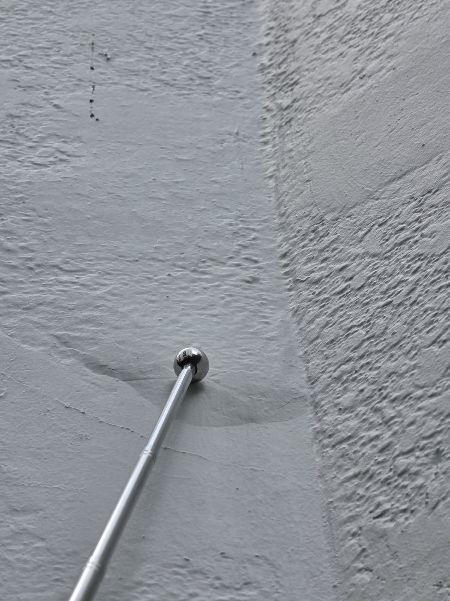 Wall crack and mallet during a close-range facade check at Jalan Labu Ayer