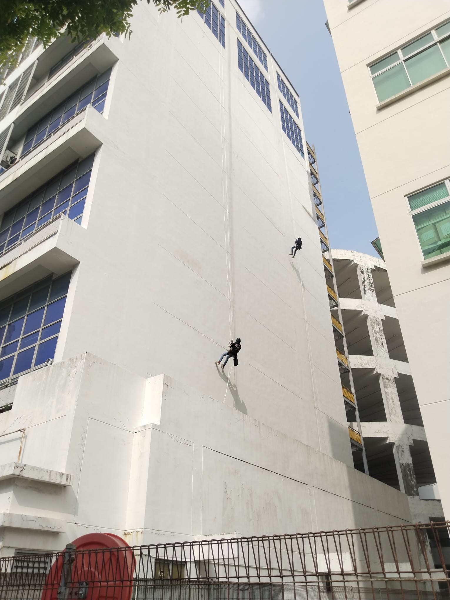 Rope-access workers on an end wall at Toh Guan Road East