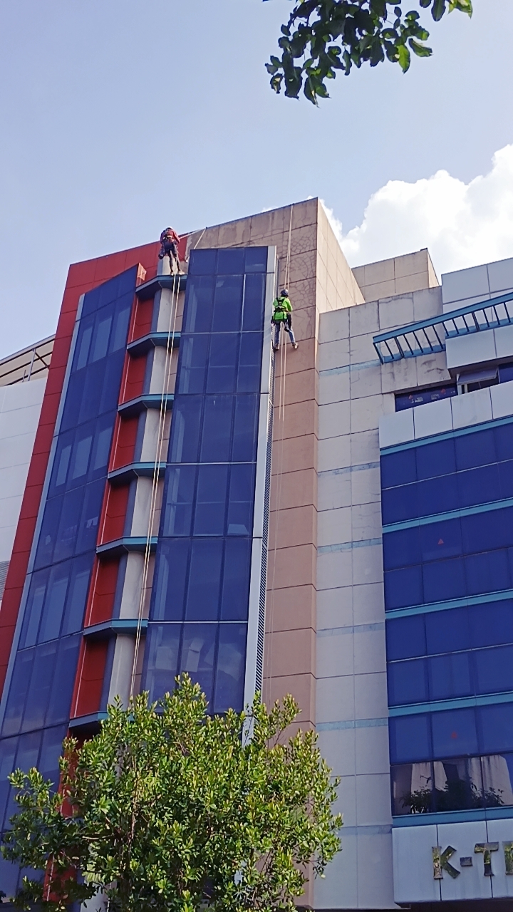 Rope-access team on the blue and red facade at Ubi Crescent